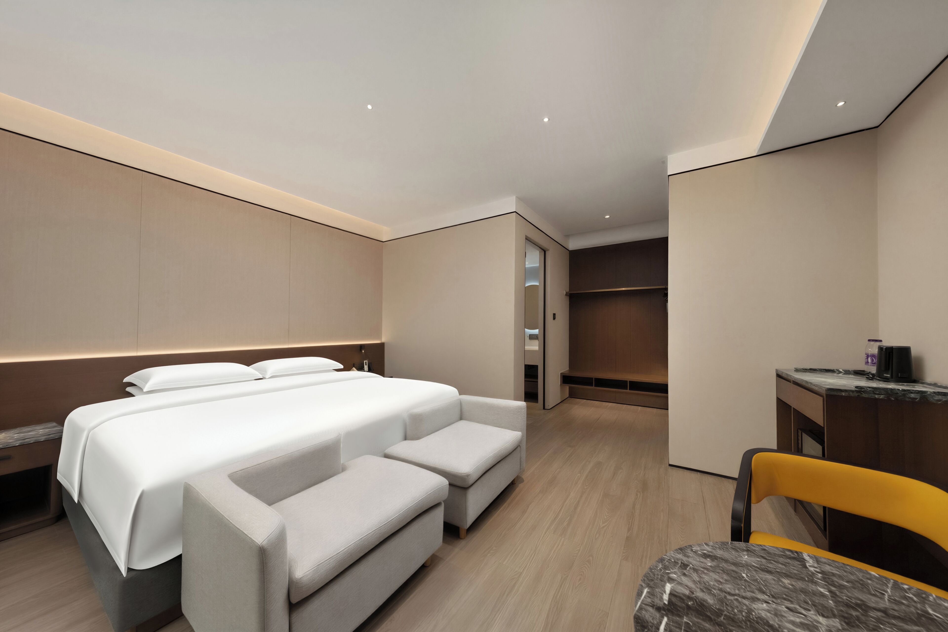 A modern hotel room with a large bed, a sofa, a desk, and a chair.
