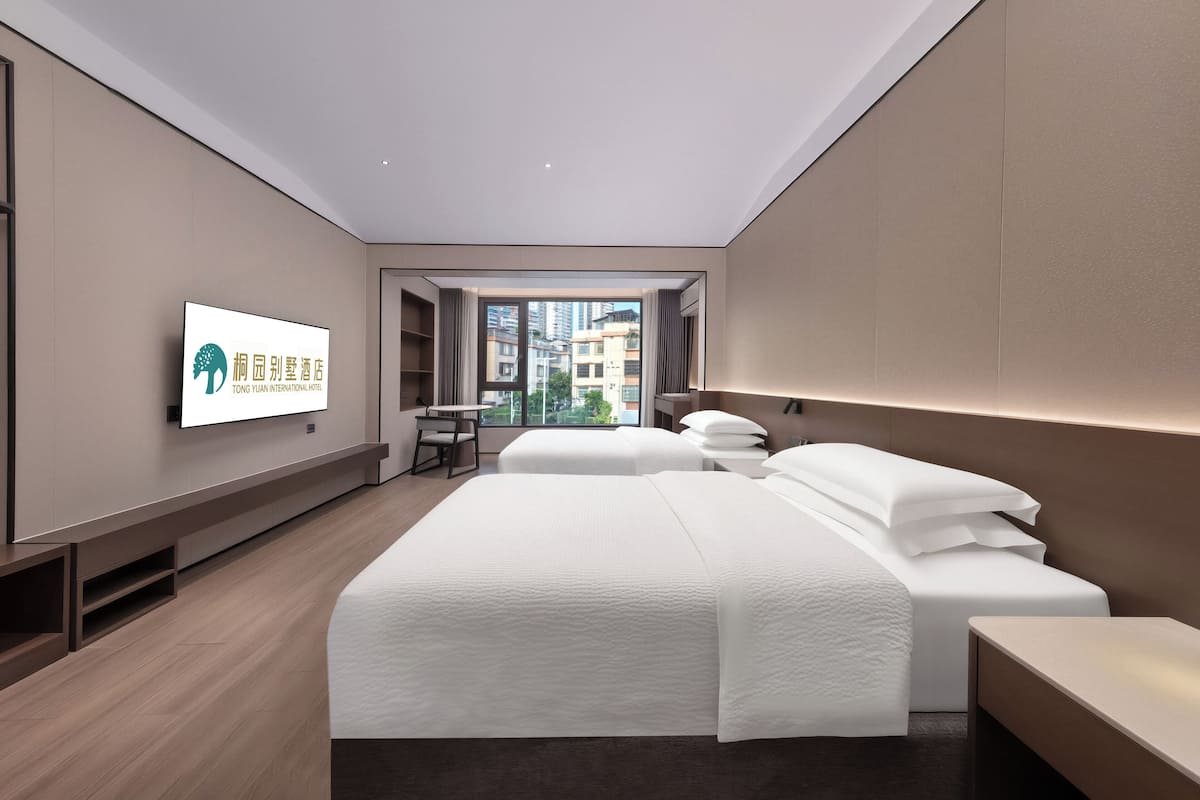 A modern hotel room with a large bed, a desk, and a TV on the wall.