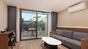 A modern hotel room with a sofa, a marble coffee table, a desk with chairs, and a sliding glass door leading to an outdoor area with a table and chairs. - Tong Yuan International Hotel Guangzhou East Railway Station Meihuayuan Subway Station Branch  (Guangzhou)