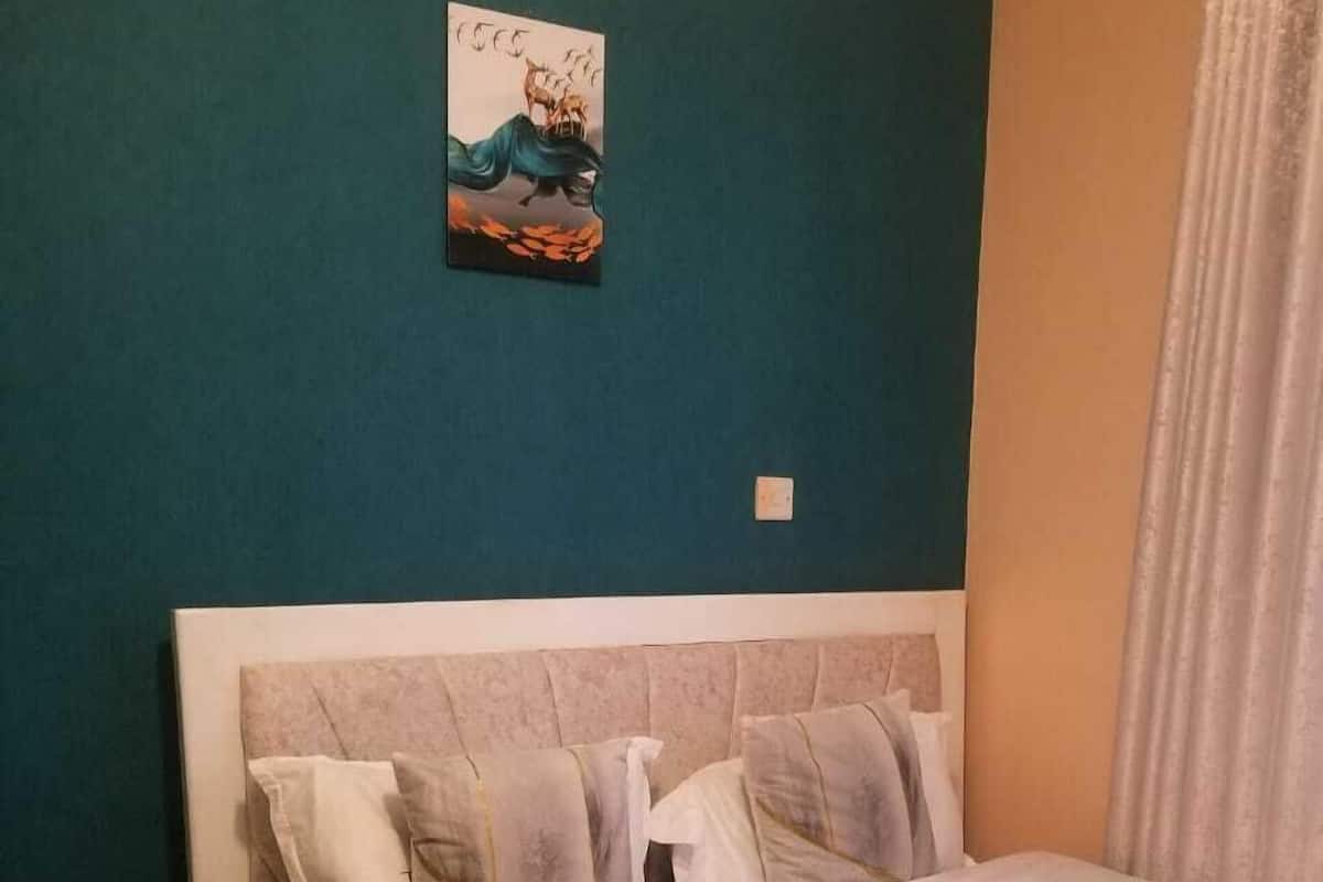 Un dormitorio con cama, mesita de noche y un cuadro colgado en la pared.