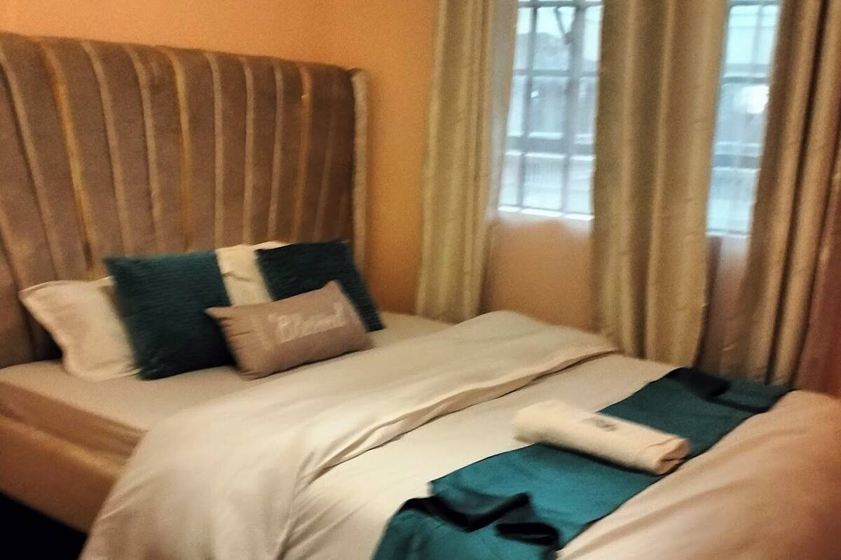 Una habitación de hotel con cama, almohadas y ventana con cortinas.