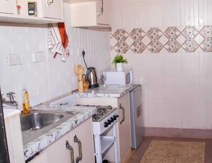 Een koelkast, een microgolfoven, kookgerei, borden en bestek