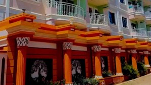 A row of colorful hotel buildings with balconies and a tree silhouette on the facade. - Paradise Apartments Embu (Embu)
