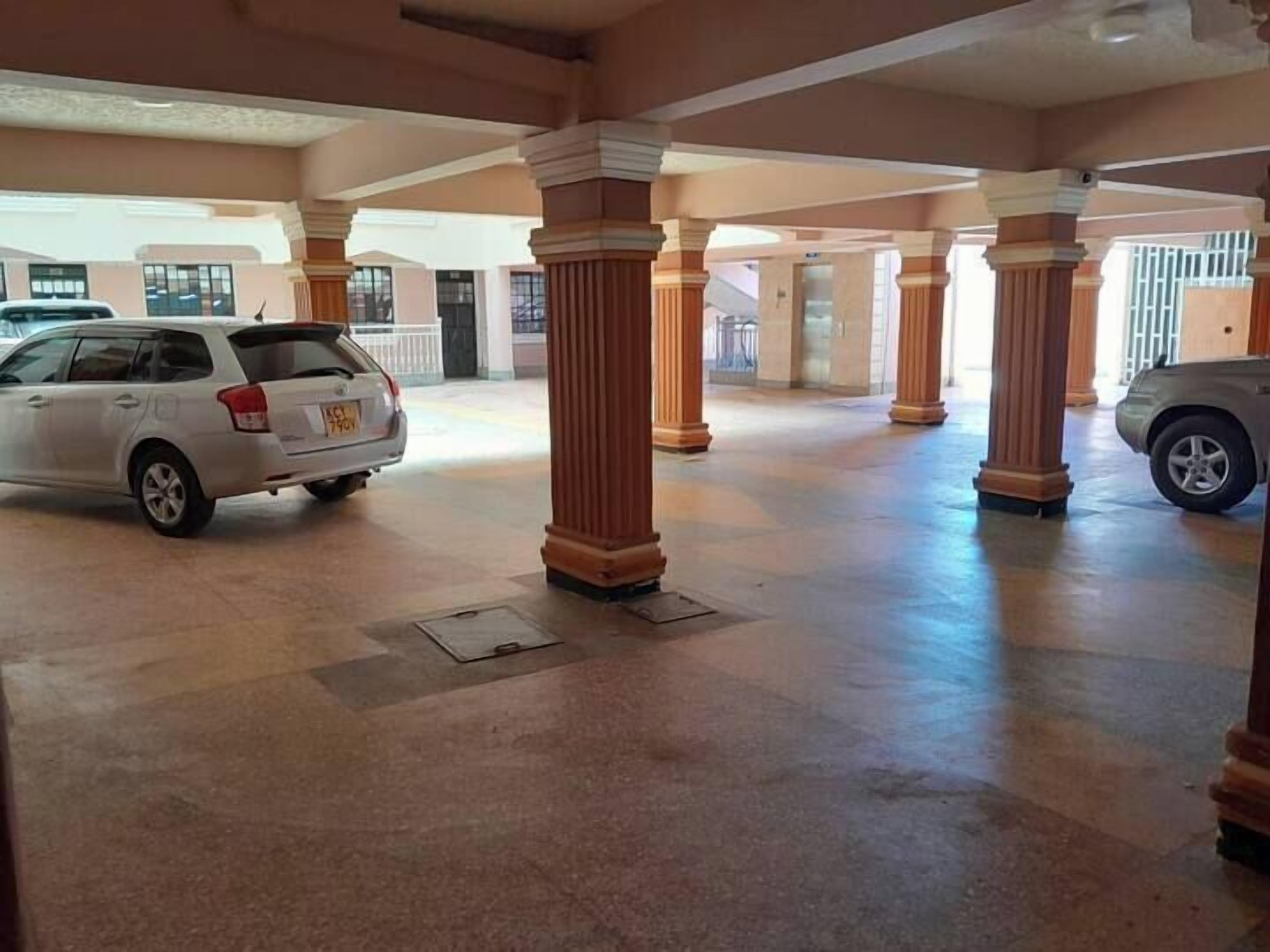 A spacious indoor area with columns and a car parked in the background.