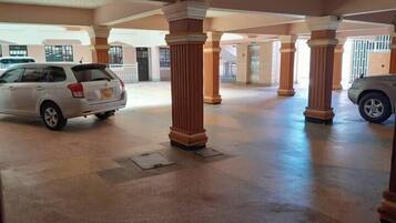 A spacious indoor area with columns and a car parked in the background.