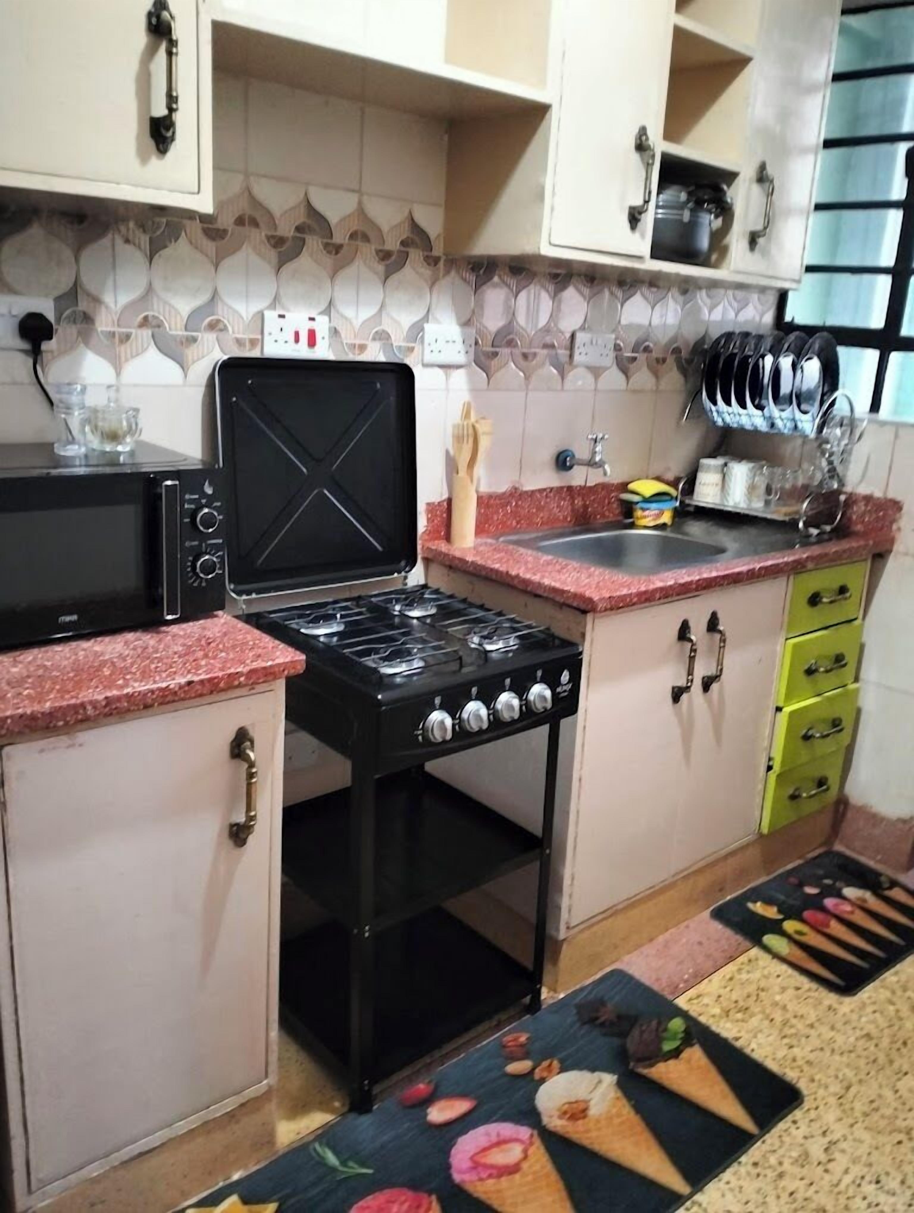 Una cucina con fornello, forno a microonde e pensili.
