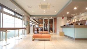 A spacious lobby with a reception desk, a seating area with a bench, and a large window providing natural light. - HOTEL CUORE TSURUGA (Tsuruga)
