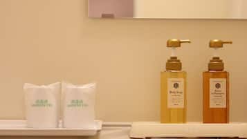 Un baño con dos botellas de jabón corporal y dos bolsas desinfectadas sobre una bandeja blanca.