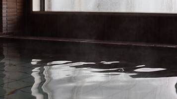 A wet floor with a reflection of a window and a brick wall.