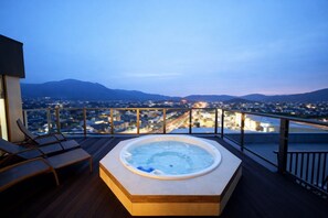 A hot tub on a wooden deck with a cityscape view at dusk. - HOTEL CUORE TSURUGA (Tsuruga)