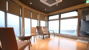 A room with large windows, wicker chairs, a glass table, and a wooden floor. - HOTEL CUORE TSURUGA (Tsuruga)