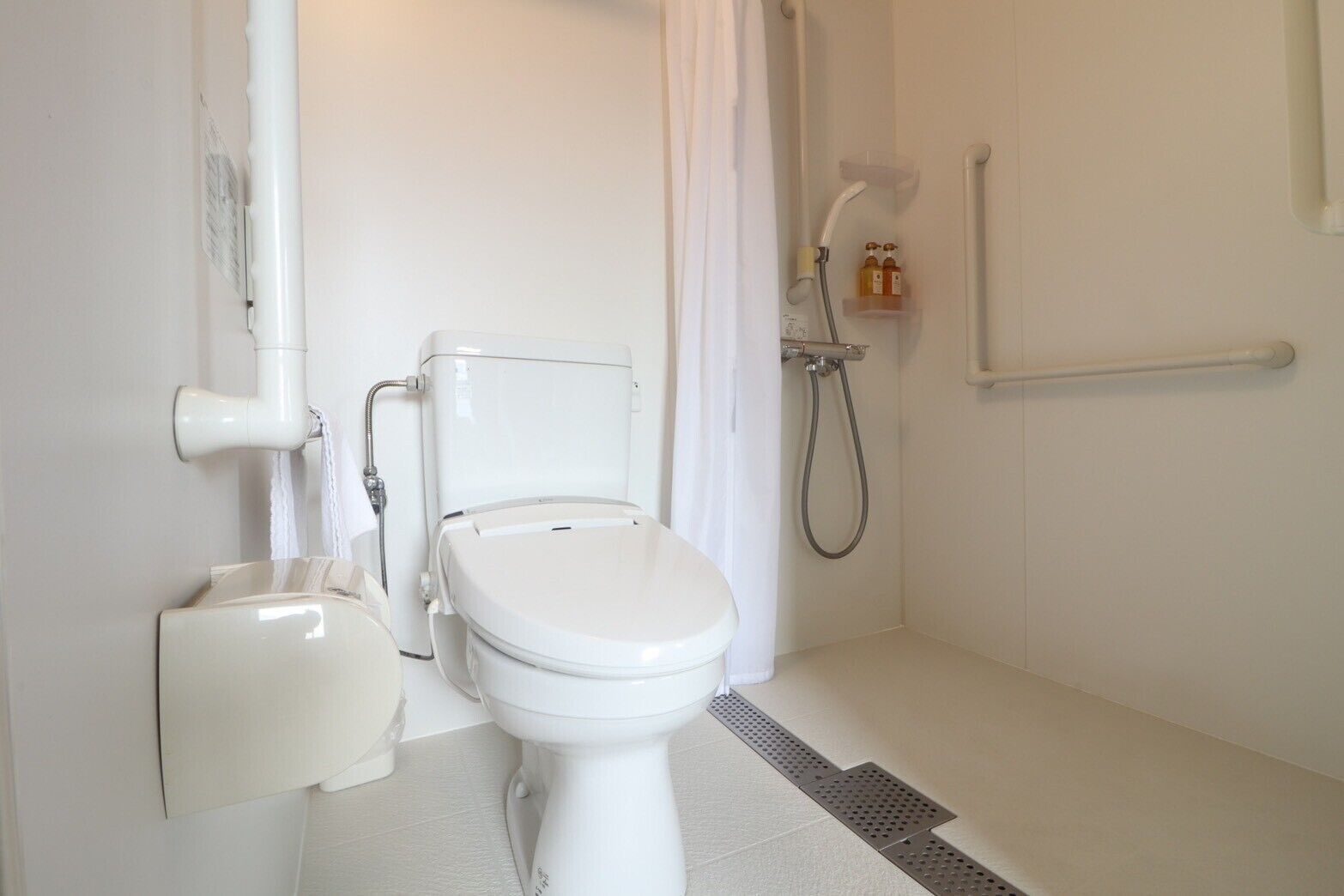 A bathroom with a toilet, a shower, and a hand dryer.