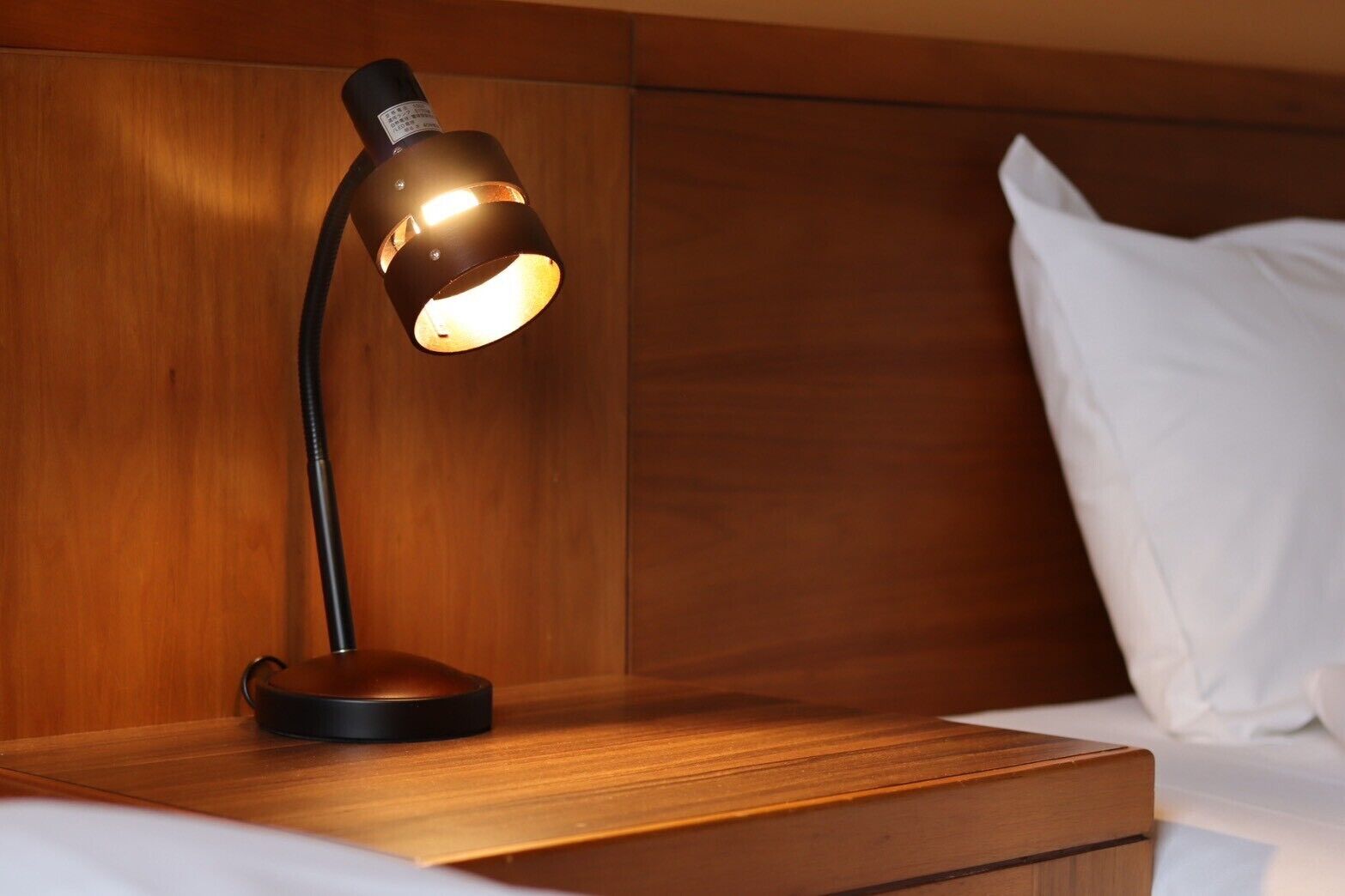 Ein Nachttisch aus Holz mit einer modernen Schreibtischlampe.