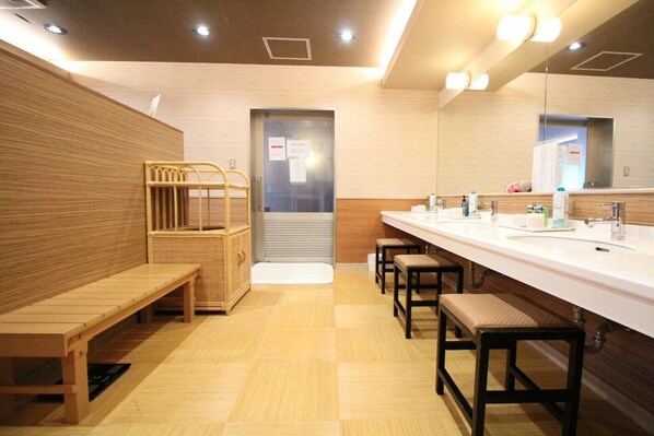 A modern bathroom with a long bench, a sink area with stools, and a mirror. - HOTEL CUORE TSURUGA (Tsuruga)