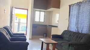 A living room with a sofa, a coffee table, and a ceiling fan. - SS Home Stay (Bengaluru)