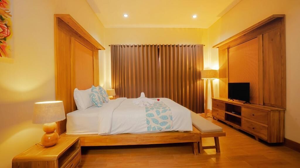 A hotel room with a wooden bed, a bench, a TV, and a wooden cabinet.