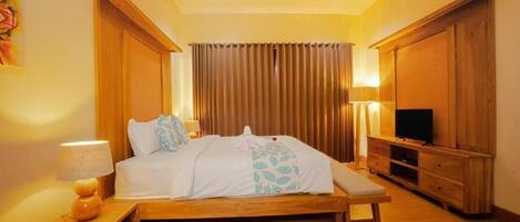 A hotel room with a wooden bed, a bench, a TV, and a wooden cabinet.