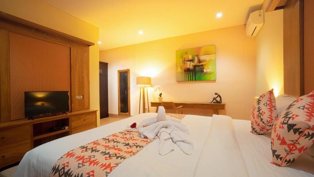 Habitación de hotel con cama, televisor, escritorio y un cuadro en la pared.