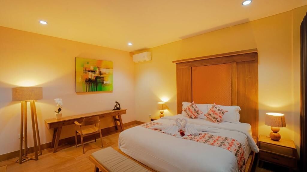 A hotel room with a large bed, bedside tables, a desk, and a chair.