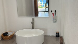 Un bagno con un lavandino bianco, un mobile contenitore in legno e uno specchio grande.