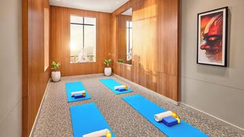 A yoga room with wooden walls, large windows, and blue mats.