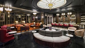 Et luksuriøst loungeområde med læderpolstrede møbler, en bar og en stor lysekrone.