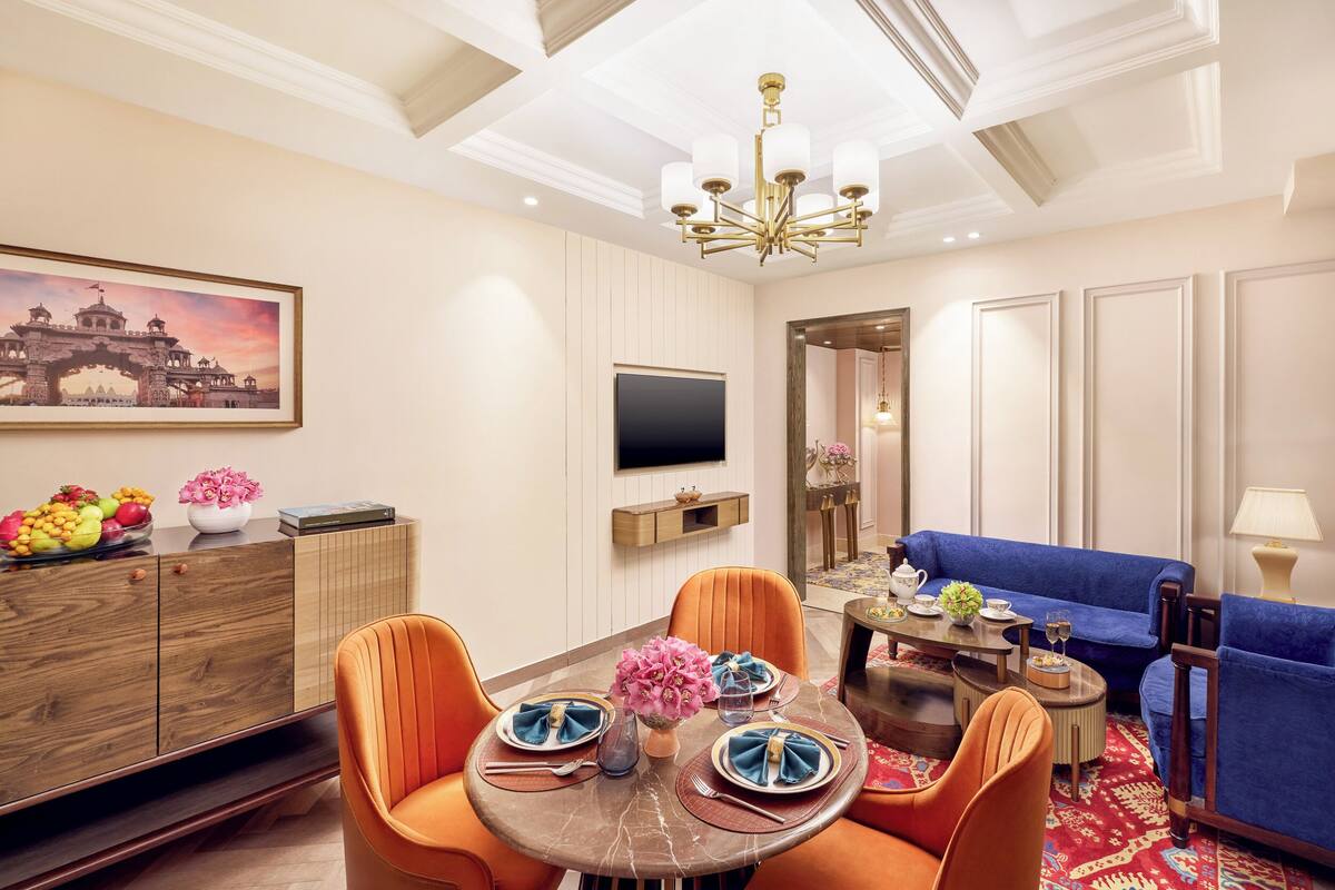 A dining area with a round table, orange chairs, and a blue sofa.