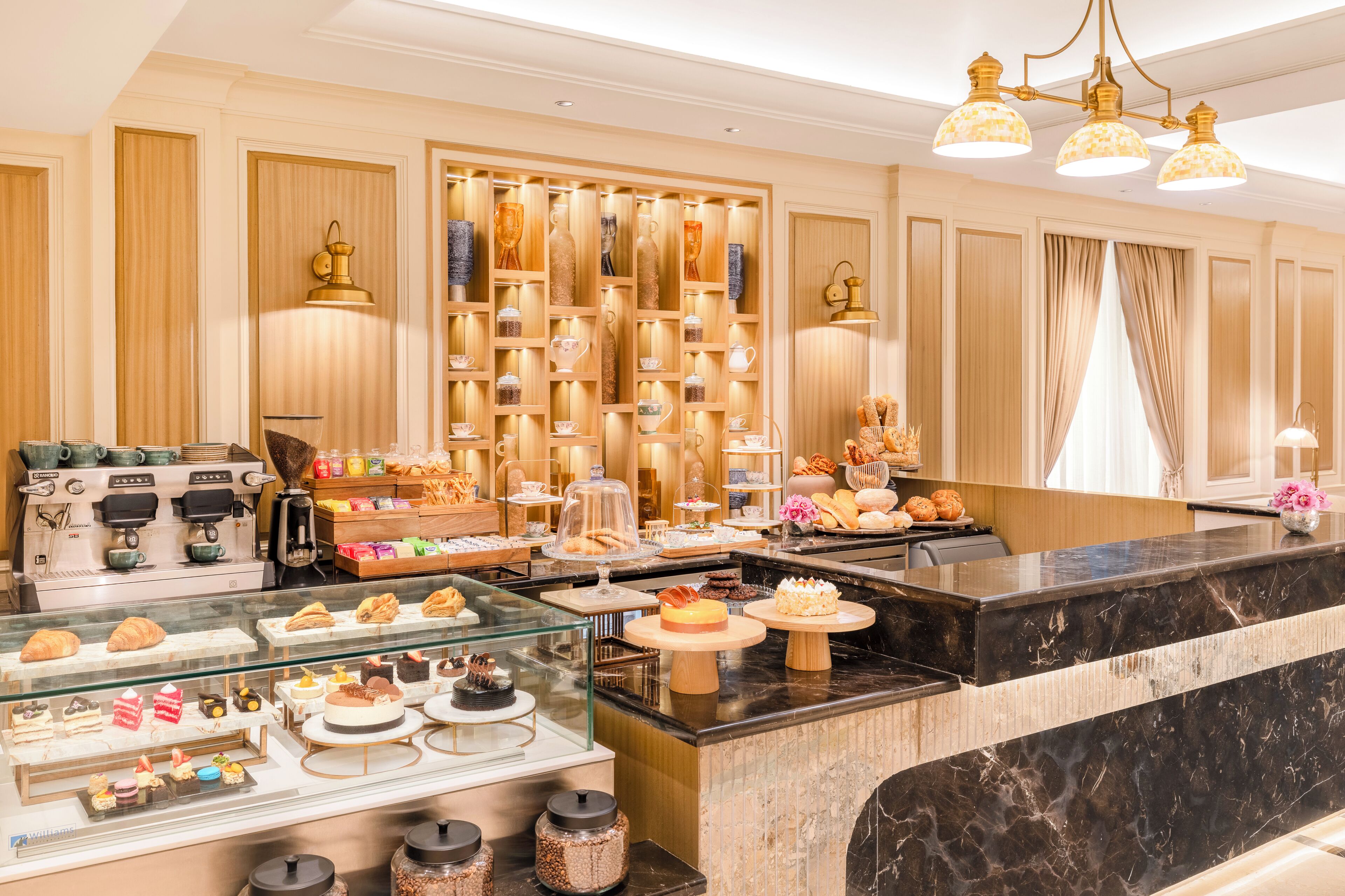 A bakery counter with pastries and desserts, a coffee machine, and a display of baked goods.