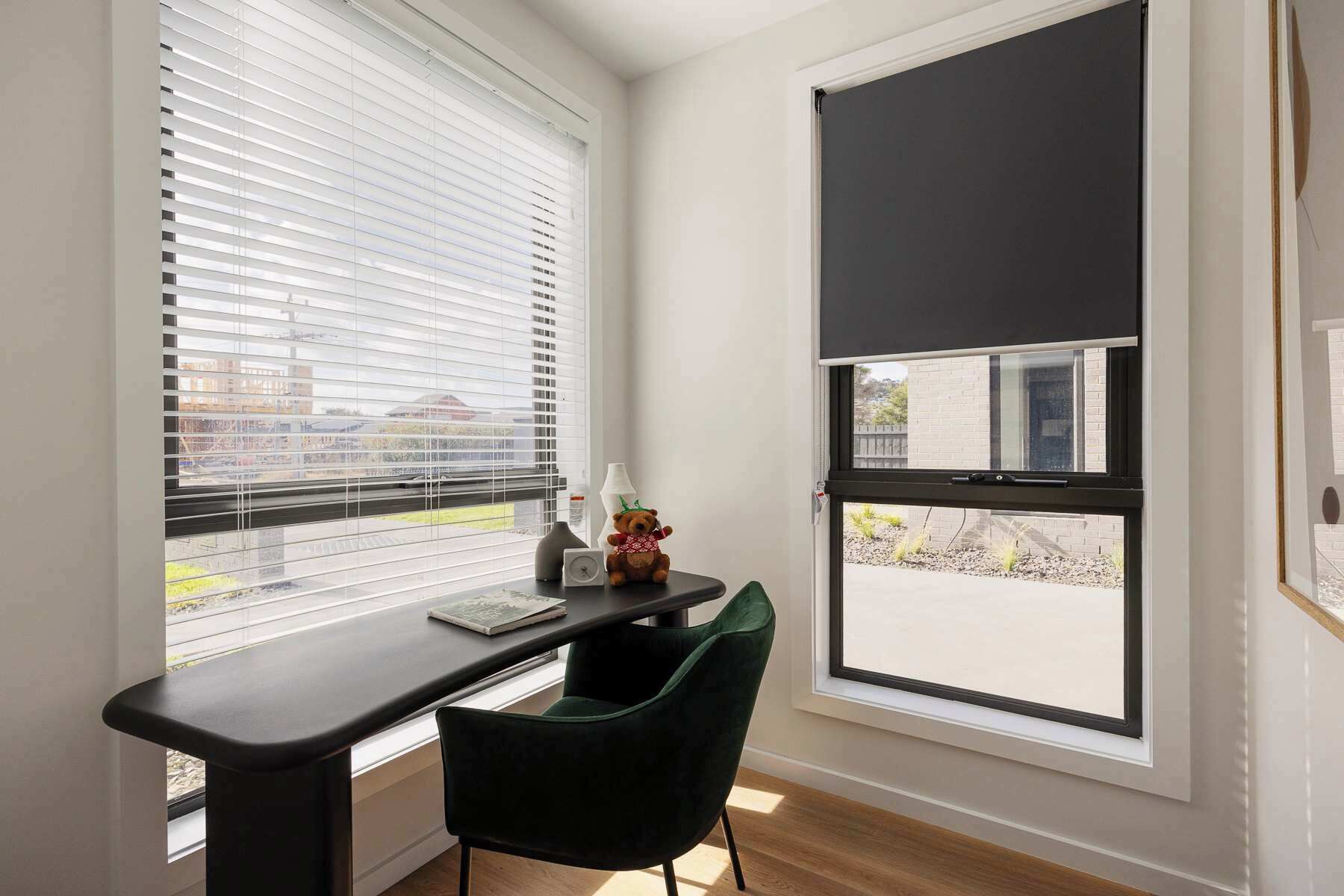 A modern room with a desk, chair, and two windows with blinds.