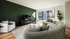 A modern living room with a green accent wall, a large window, and a view of the outdoors. - Rooftop Deck & Sauna, 350m to Safety Beach (Safety Beach)