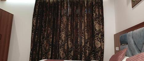 A bedroom with a bed, curtains, and a headboard.