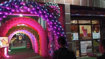 Una entrada decorada con un arco de globos de colores y un letrero que dice 'Maxchef Multicuisine Veg Restor & Cafe'.