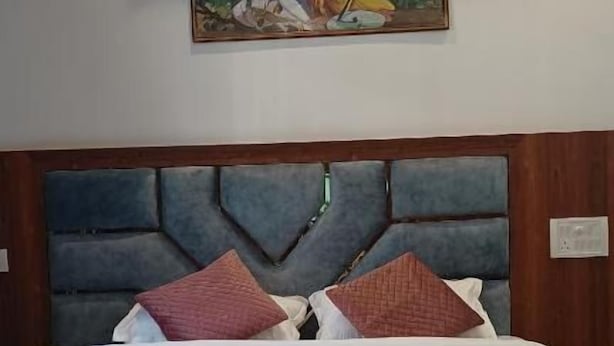 Un lit avec une tête de lit, des oreillers et une couverture.