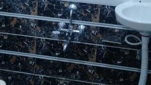 A bathroom with a black and white tiled wall, a white sink, and a shower area. - HOTEL JASRAJ (Ahmedabad)