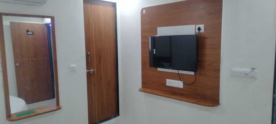 Ένα δωμάτιο με μια ξύλινη πόρτα, έναν καθρέφτη και μια τηλεόραση τοποθετημένη στον τοίχο.