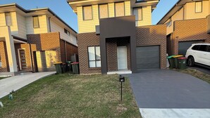 A modern two-story residential building with a flat roof, brick facade, and a garage.