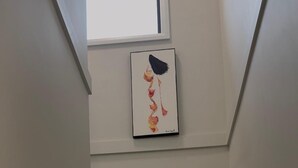A staircase with wooden steps and white handrails, leading to a landing with a framed artwork.