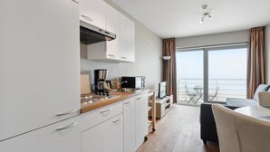 Een moderne keuken met witte kastjes, een koffiezetapparaat en uitzicht op het balkon.
