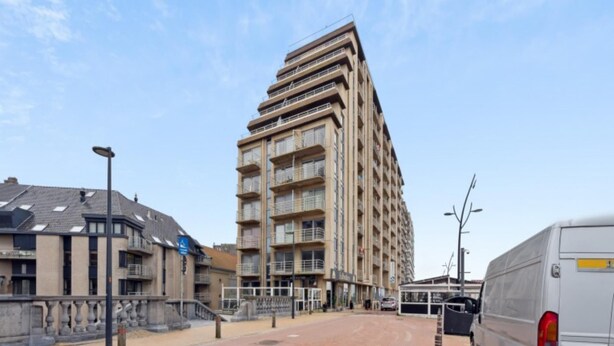 A multi-story building with balconies, a paved area, and a parked van. - Nice studio near the beach (Blankenberge)