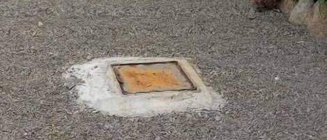 Um edifício com um caminho de cascalho que leva a uma porta, rodeado por vegetação e um céu claro.