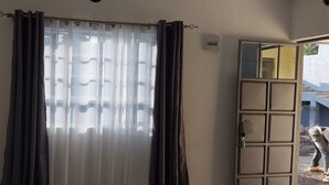 A room with a large window covered by sheer curtains and a dark drape, a door with a mirror, and a visible electrical outlet on the wall. - Maara Lodge Chogoria (Chogoria)