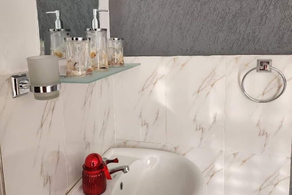 Un baño con lavamanos blanco, espejo y ducha.