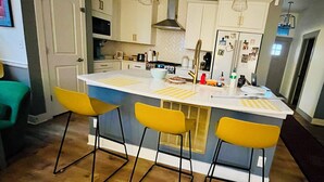 Una cucina moderna con isola centrale, sgabelli da bar e illuminazione a sospensione.