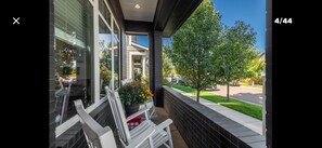 A modern building with a covered porch, outdoor seating, and a view of a residential street. - Spacious, bright & cozy Central Park 5 BR Home Away from Home near UC-Anschutz (Denver)