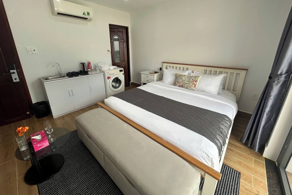 Een hotelkamer met een bed, een wasmachine, een kleine kitchenette en een badkamer.