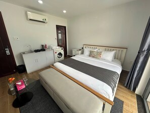 Ein Hotelzimmer mit Bett, Waschmaschine, einer kleinen Küchenzeile und einem Badezimmer.