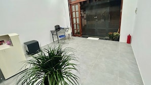 Habitació petita i senzilla amb escriptori, cadira i una planta en test.