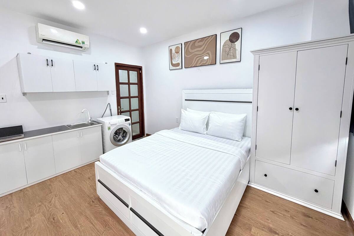 Een slaapkamer met een bed, een kledingkast, een wasmachine en een deur.