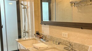 A modern bathroom with dual sinks, a glass shower enclosure, and a large mirror. - Gio Hotel in Hue (Hue)
