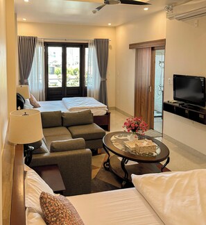 A hotel room with a bed, sofa, TV, and a table with a vase. - Gio Hotel in Hue (Hue)